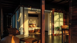 Um quarto com cama, uma cadeira de madeira, uma mesa e um vaso de planta.