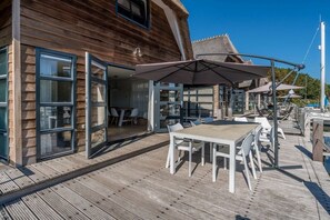 Ein Holzgebäude mit einer Glastür, die auf einen Außenbereich mit Tisch und Stühlen führt.