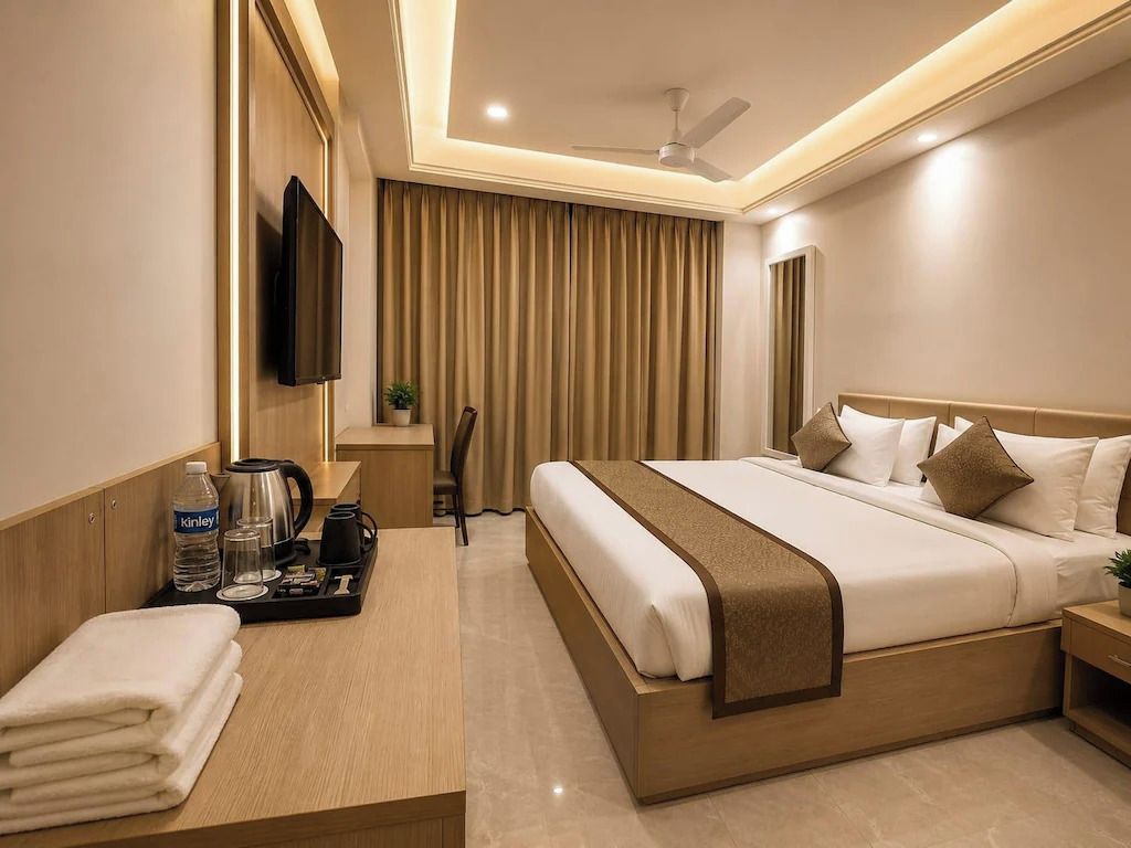 A hotel room with a bed, bedside table, TV, curtains, and a ceiling fan.