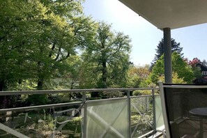 Un balcon avec vue sur les arbres et une maison en arrière-plan.