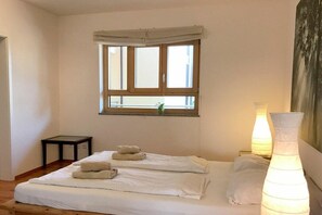 Habitació d'hotel amb un llit, una finestra amb cortines, una taula de nit i dues làmpades de nit.