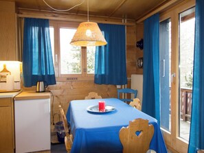 A room with a table covered in blue tablecloth, a red candle on a plate, a wicker lamp, and wooden walls. - Cresta di Saas Appartement/Fewo 6-Bettwohnung by Interhome (Saas-Fee)