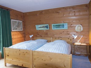 A wooden cabin room with two wooden beds, a small table with a lamp, and three framed pictures on the wall. - Cresta di Saas Appartement/Fewo 6-Bettwohnung by Interhome (Saas-Fee)