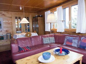 A cozy cabin interior with a leather sofa, a wooden table with a bowl and candle, and a dining area with a table and chairs. - Cresta di Saas Appartement/Fewo 6-Bettwohnung by Interhome (Saas-Fee)