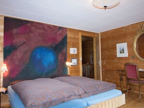 Ein Schlafzimmer mit einem großen Bett, einer Holzwand, einem Spiegel und einer Tür zu einem anderen Raum.