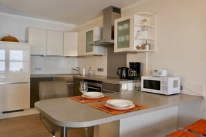 Uma cozinha moderna com armários brancos, micro-ondas e cafeteira.