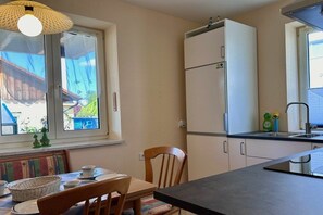A compact kitchen with a refrigerator, a sink, and a dining area with a table and chairs. - Uschi's Summer Garden (Wangen im Allgäu)