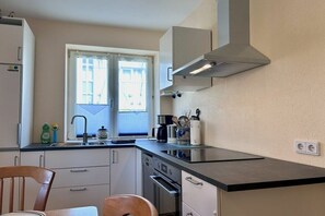 A kitchen with a stove, oven, and sink. There is a window with blinds, and a chair is visible. - Uschi's Summer Garden (Wangen im Allgäu)