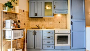 Una cocina con armarios azul claro, un microondas, un tostador y un lavamanos.