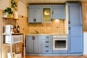 A kitchen with light blue cabinets, a microwave, a toaster, and a sink. - Casa Sassolino - Torre Cajetani (Torre Cajetani)