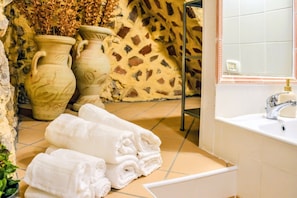 A bathroom with a bathtub, a sink, and two large vases on the floor. - Casa Sassolino - Torre Cajetani (Torre Cajetani)