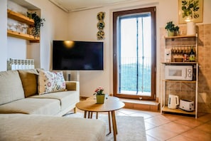 A living room with a sofa, a coffee table, a TV, and a balcony door. - Casa Sassolino - Torre Cajetani (Torre Cajetani)