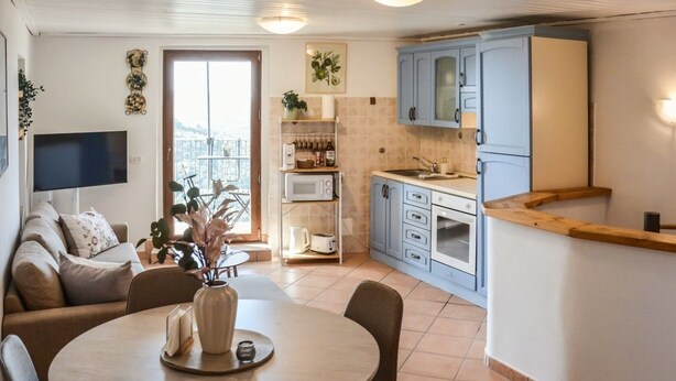 Un espacio habitable compacto con comedor, kitchenette y balcón con vistas.