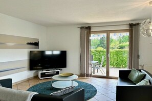 Ett modernt vardagsrum med en platt-TV, ett runt soffbord och en soffa.