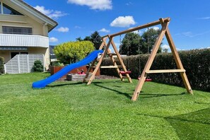A wooden swing set with a blue slide in a grassy yard. - Holiday apartment with 1 bedroom (Sigmarszell)