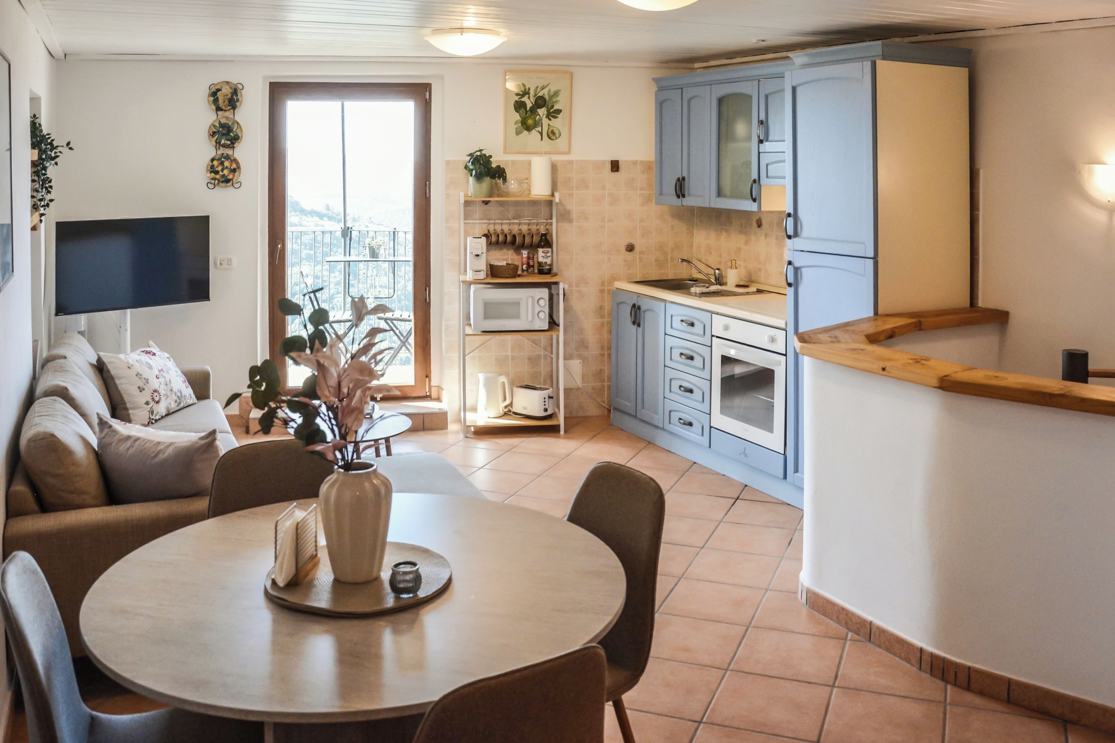 Un espacio habitable compacto con comedor, kitchenette y balcón con vistas.