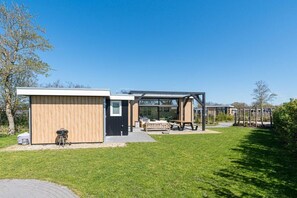 Ein modernes Haus mit einer Terrassenfläche, einem Grill und einer Holzterrasse.