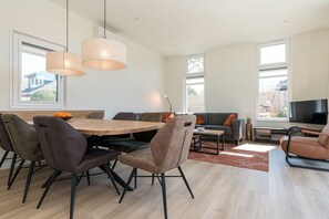 Ein moderner Wohnbereich mit Essplatz, Sitzgelegenheiten und einem Fernseher.