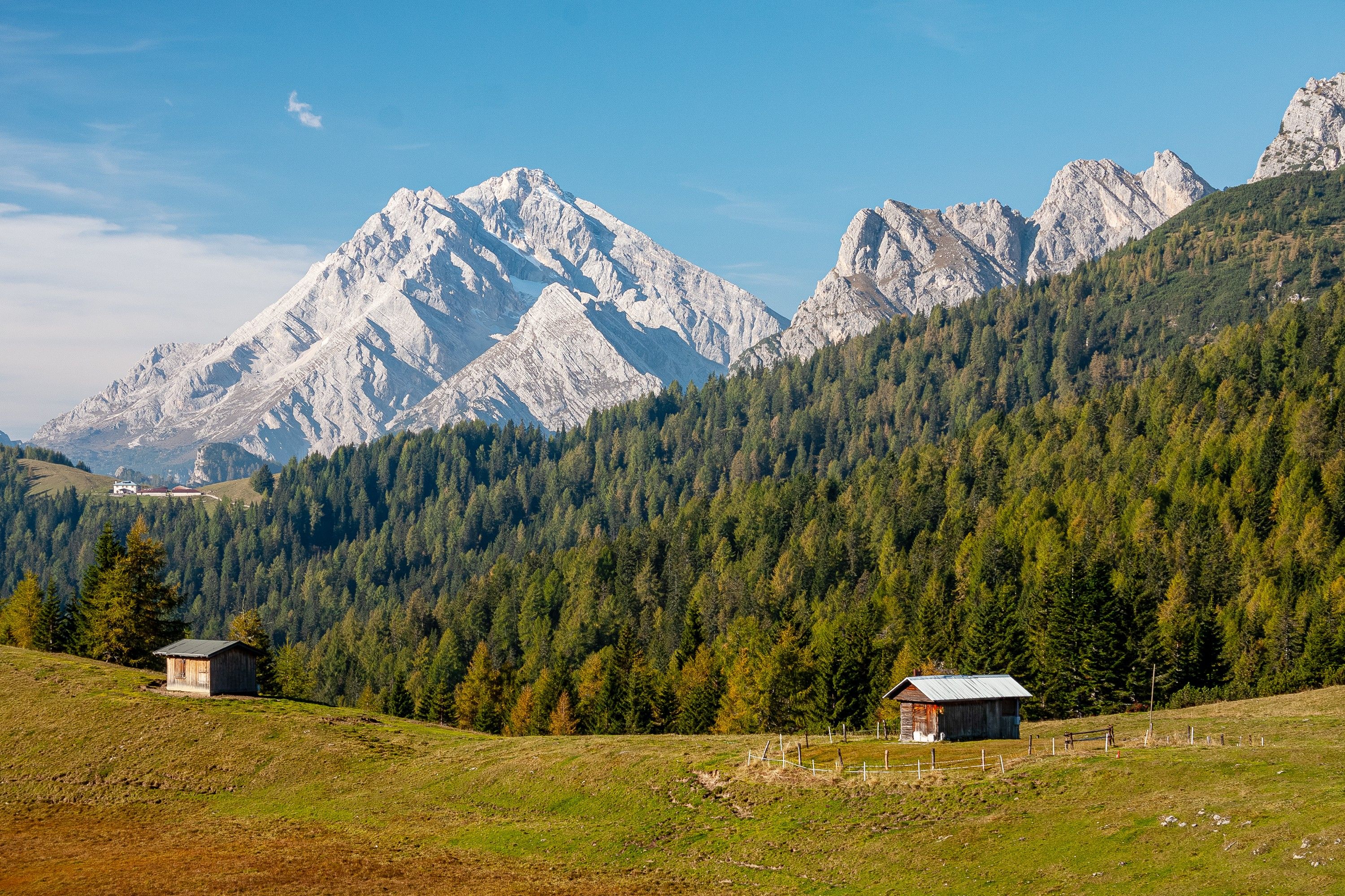 Un paysage montagneux avec deux cabanes rustiques et un ciel dégagé.