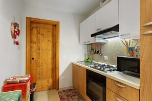 Une cuisine compacte avec des meubles de rangement en bois, une cuisinière à gaz, un four à micro-ondes et un petit évier.