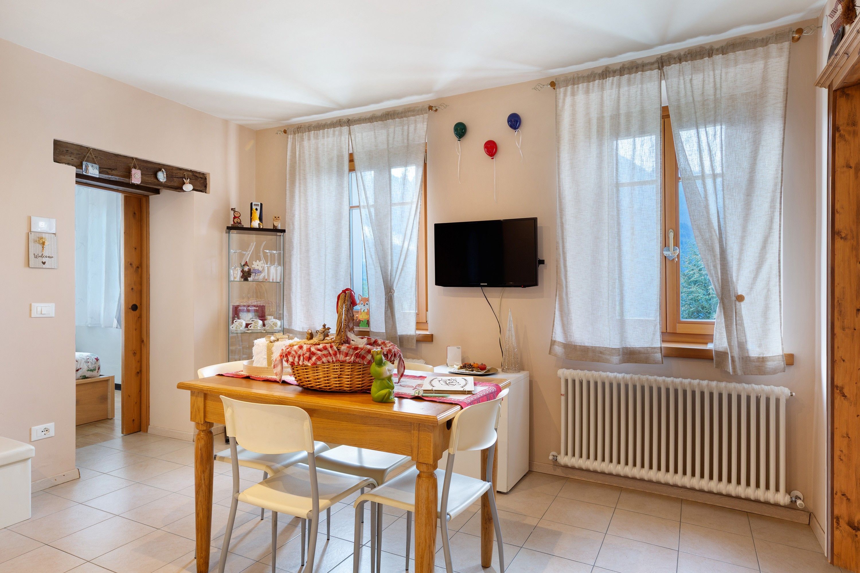 Ein Essbereich mit Tisch, Stühlen, einem Korb und einem Fernseher an der Wand.