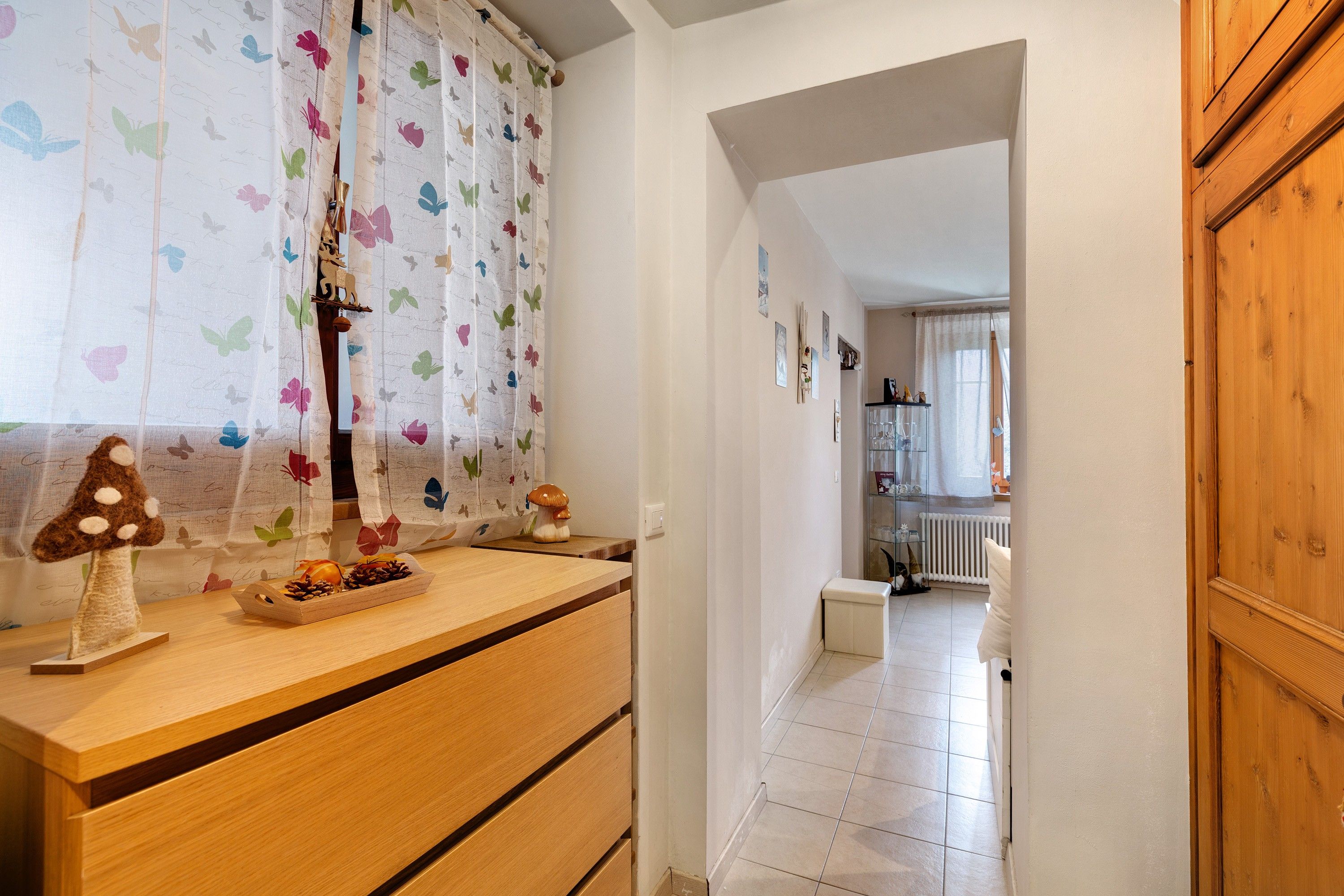 A hallway with a wooden counter, a decorative mushroom, and a butterfly curtain.