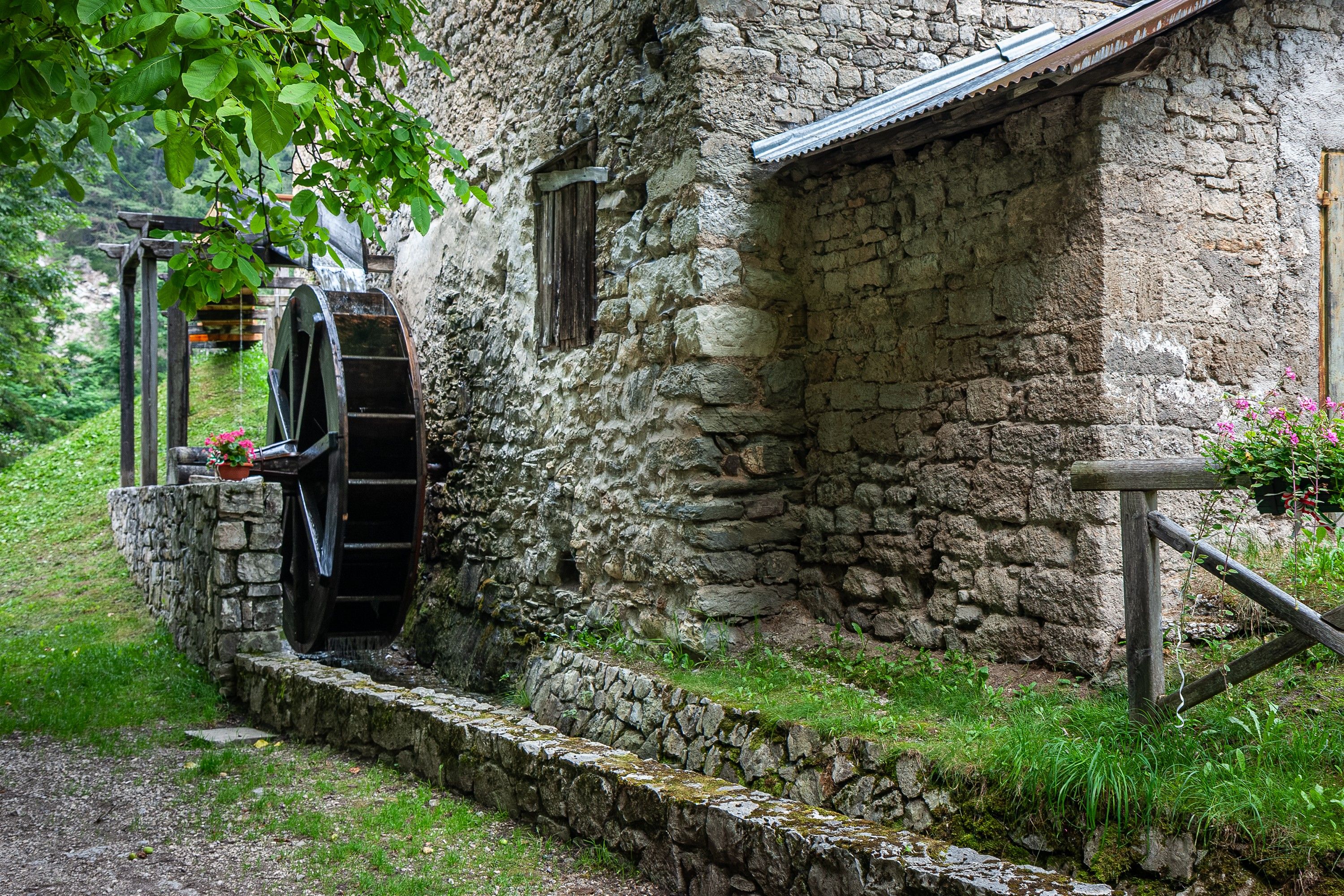 Un rustico edificio in pietra con una grande ruota idraulica integrata in una parete di pietra.