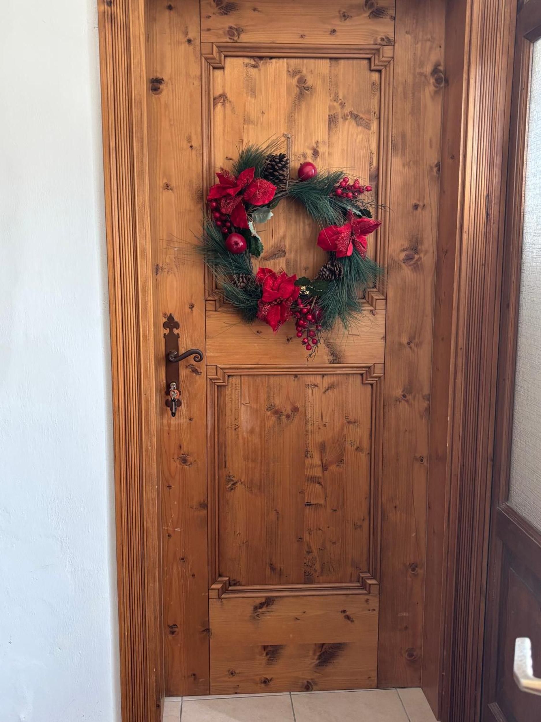 Una puerta de madera con un adorno de guirnalda y un picaporte.