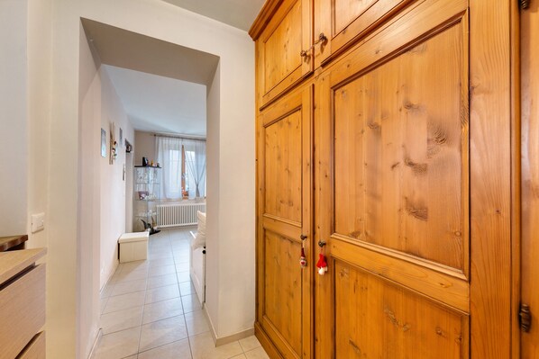 A hallway with a wooden wardrobe, a radiator, and a glass display cabinet.