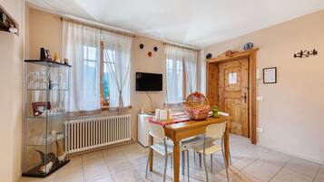 A dining area with a table, chairs, a television, and a window with curtains.