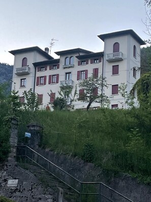 Ein mehrstöckiges Gebäude mit Balkonen, umgeben von viel Grün.