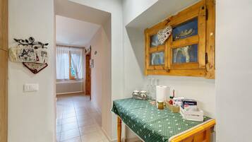 A kitchen with a wooden table, a window with a decorative item, and a hallway leading to another room.