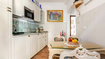 Una cocina con armarios blancos, un microondas y salpicadero de azulejos.