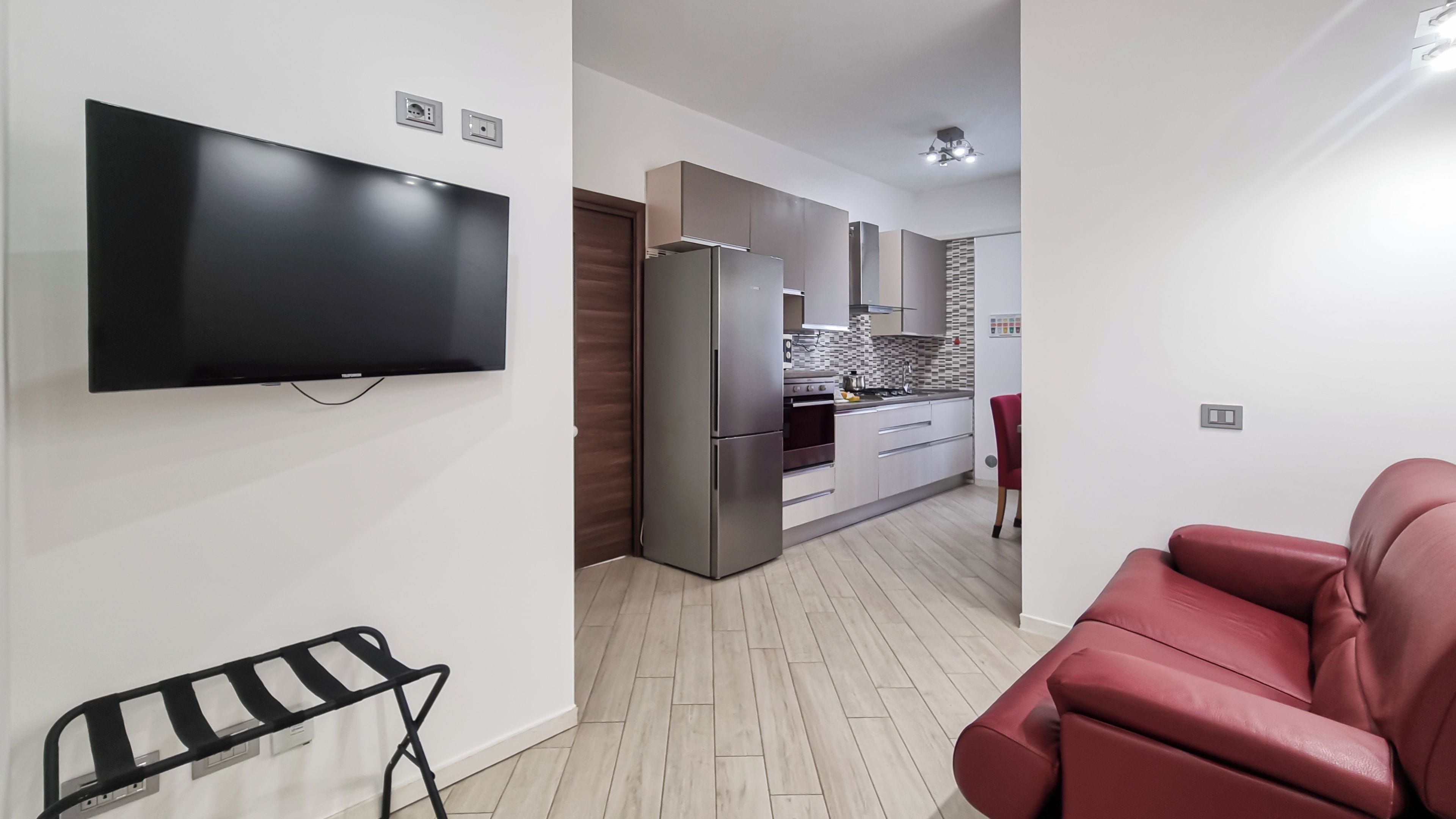 Ein modernes Wohnzimmer mit Flachbildfernseher, einem roten Sofa und einem schwarzen Metallstuhl.