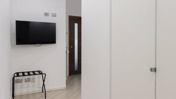 A room with a flat-screen TV mounted on the wall, a radiator, and a door leading to another room.