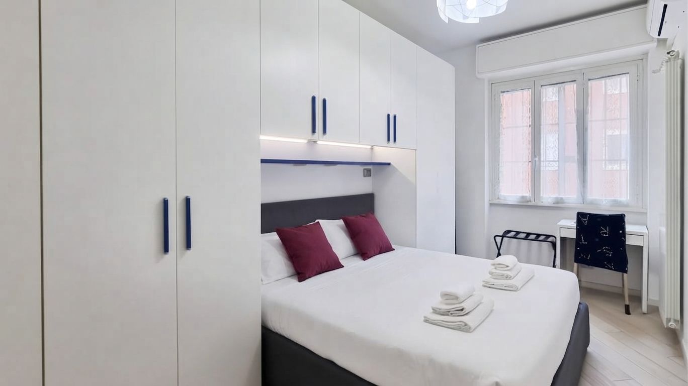 A hotel room with a bed, a desk, and a chair.