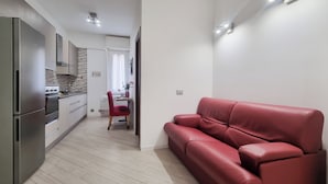 Une cuisine moderne équipée d’appareils électroménagers en acier inoxydable, un canapé en cuir rouge et un coin repas avec une chaise rouge.