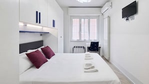 Une chambre d’hôtel avec un lit, un bureau, une chaise et un téléviseur.