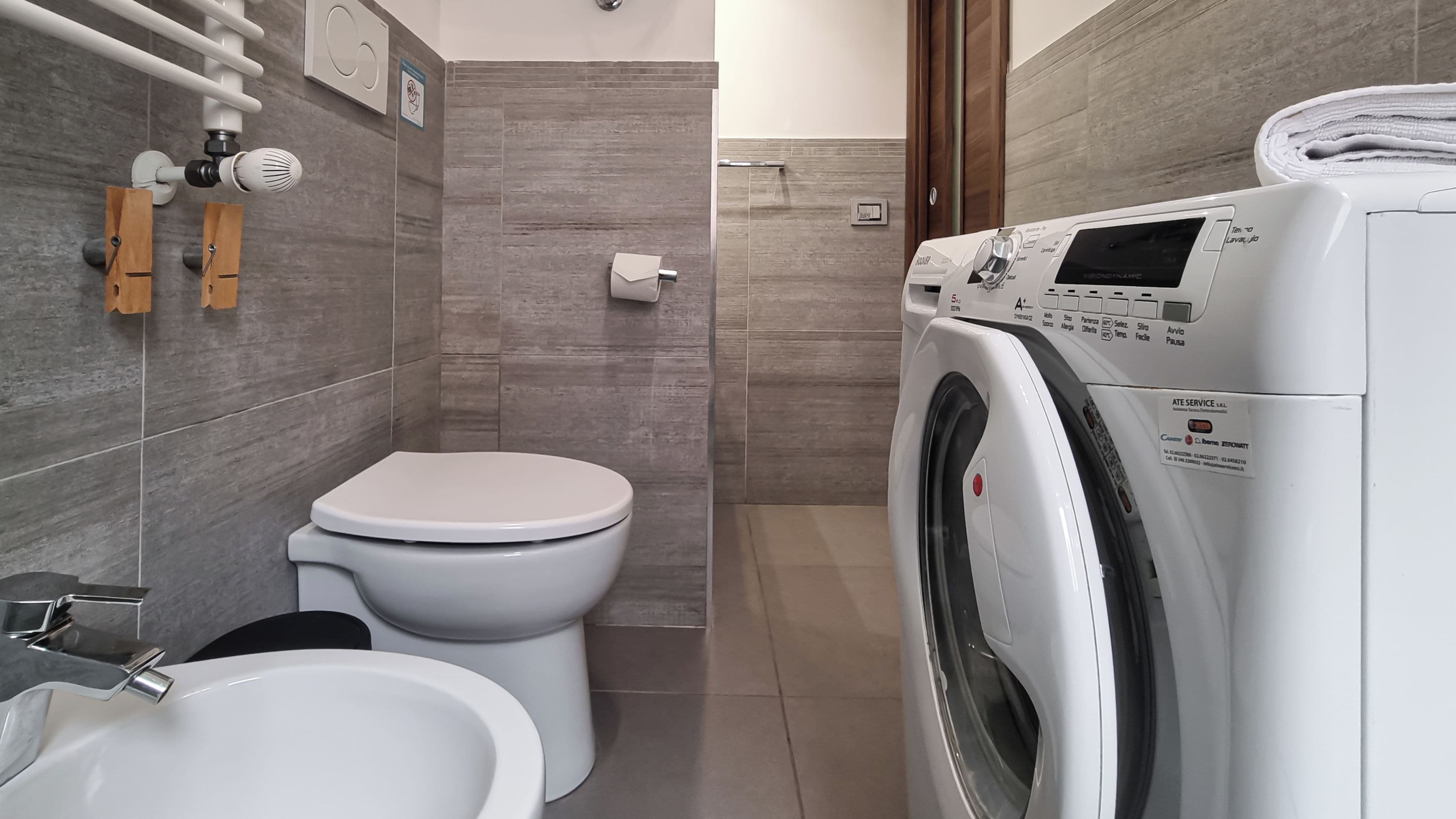 A modern bathroom with a toilet, bidet, and a front-loading washing machine.