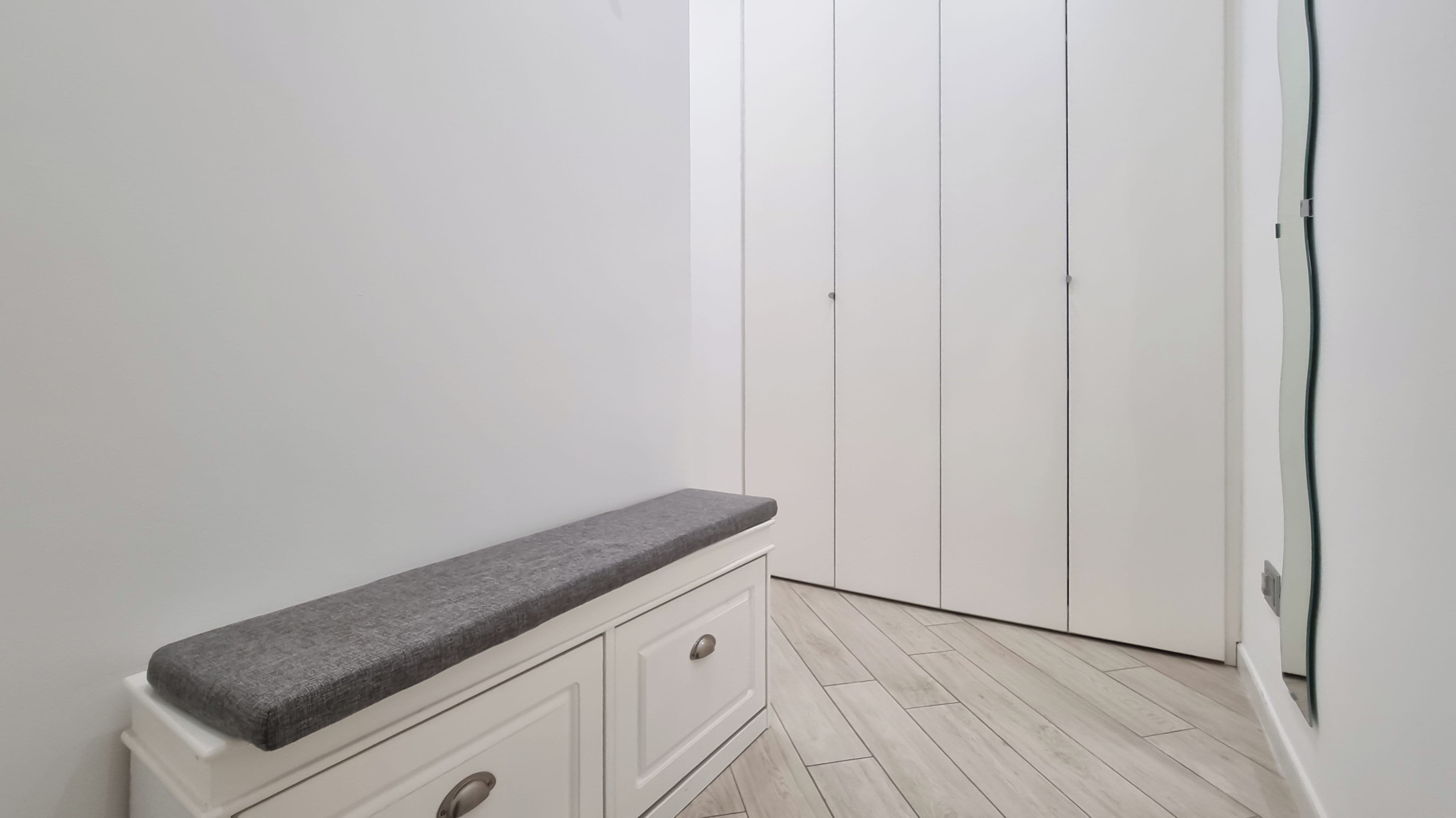 Een kamer met een bank, een witte garderobe en een deur.