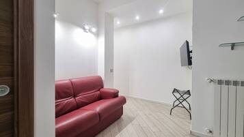 Ein modernes Interieur mit einem roten Ledersofa, einem Heizkörper und einem an der Wand befestigten Fernseher.