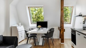 A modern kitchen with a dining table, chairs, and a view of trees through large windows. - Apartment 'Elbe Panorama View' with Balcony, Wi-Fi and Air Conditioning (Wittenberge)