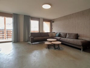 A modern living room with a sectional sofa, two round coffee tables, and large windows with curtains. - Derby Appartement/Fewo 8-Bettwohnung by Interhome (Saas-Fee)