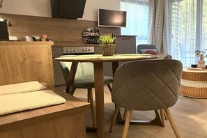 Eine moderne Küche mit Essbereich, einem an der Wand befestigten Fernseher und Blick ins Freie.