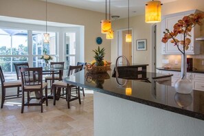 A kitchen with a central island, dining chairs, pendant lights, and a view to the outside. - Villa in Cape Coral with swimming pool (Cape Coral)