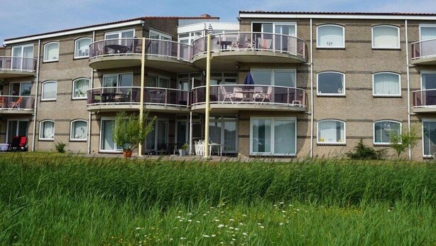Un edificio residencial de varios pisos con balcones, ventanas amplias y techo plano.