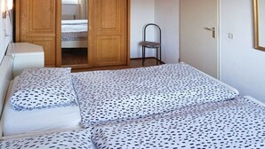 Un dormitorio con cama, armario y silla.