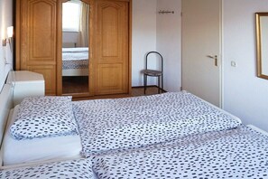 Quarto com cama, guarda-roupa e uma cadeira.