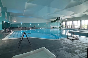 Piscina interna com vista desobstruída da área da piscina, espaço de estar e escada que leva a um nível superior.