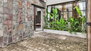 Une cour bordée de murs en pierre, dotée d’une terrasse en bois et agrémentée d’une végétation luxuriante.